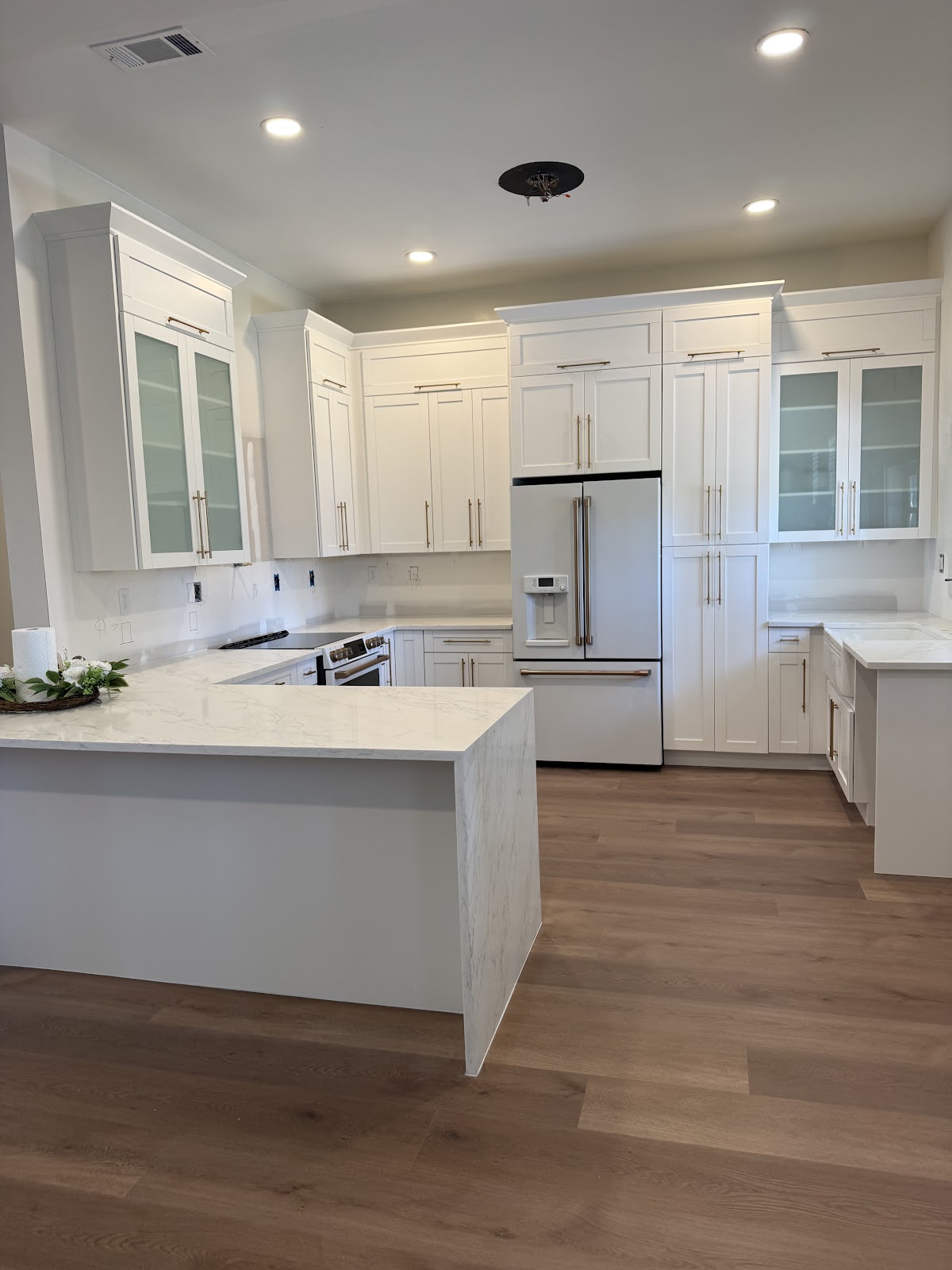 Installed white kitchen cabinets with glass-front upper doors and metal handles